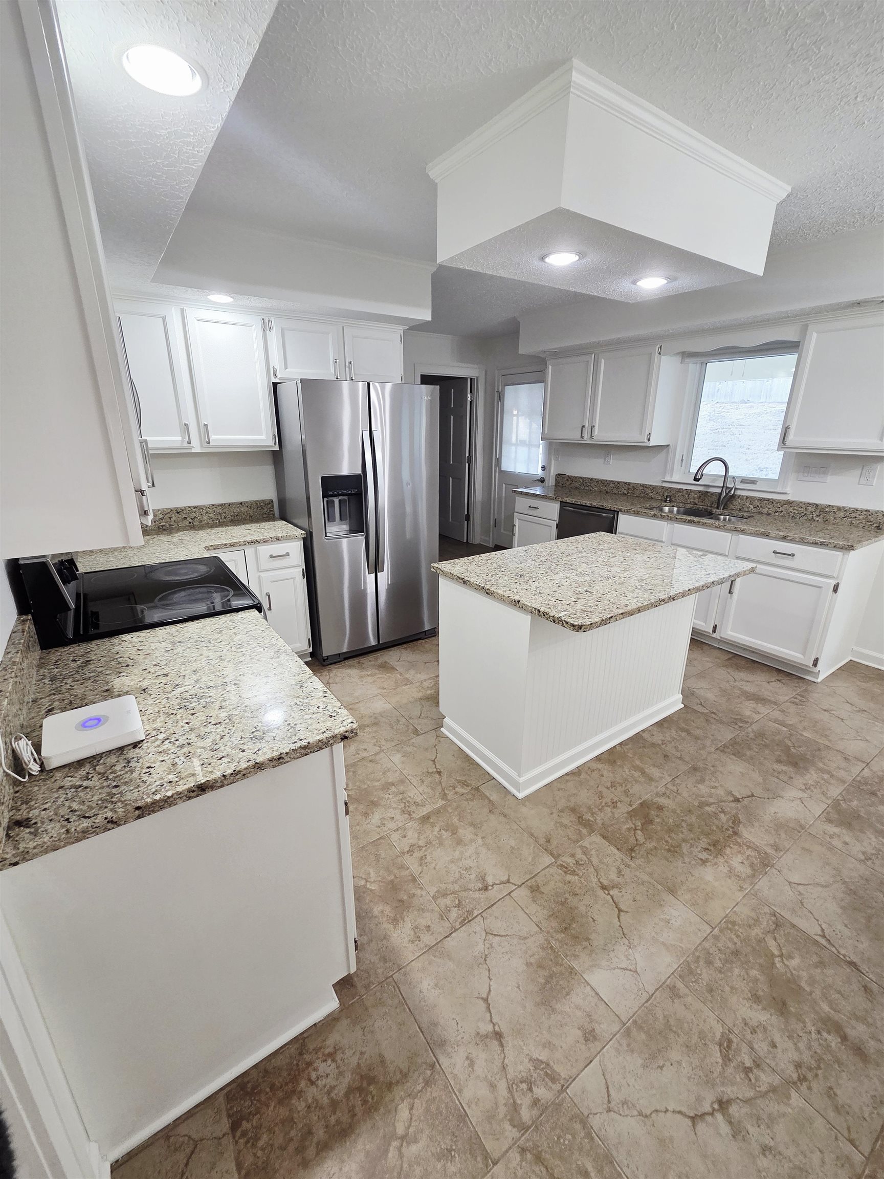 2095 Newfields Road Germantown, TN 38139 - Photo 12 of 34 Kitchen with white cabinets, black appliances, a textured ceiling, light stone countertops, and a center island