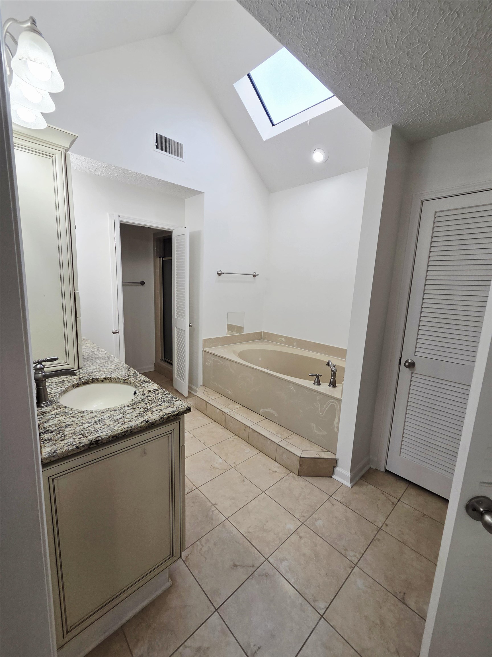 2095 Newfields Road Germantown, TN 38139 - Photo 19 of 34 Full bathroom featuring a skylight, vaulted ceiling, vanity, a garden tub, and a closet