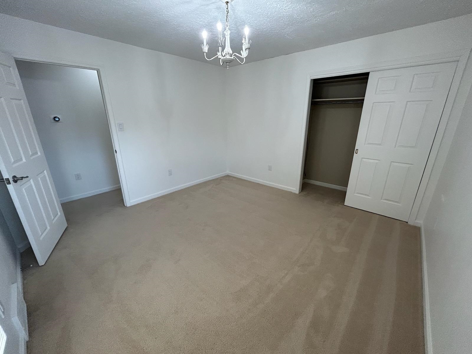 2095 Newfields Road Germantown, TN 38139 - Photo 26 of 34 Unfurnished bedroom with suspended lighting, light carpet, a closet, and a textured ceiling
