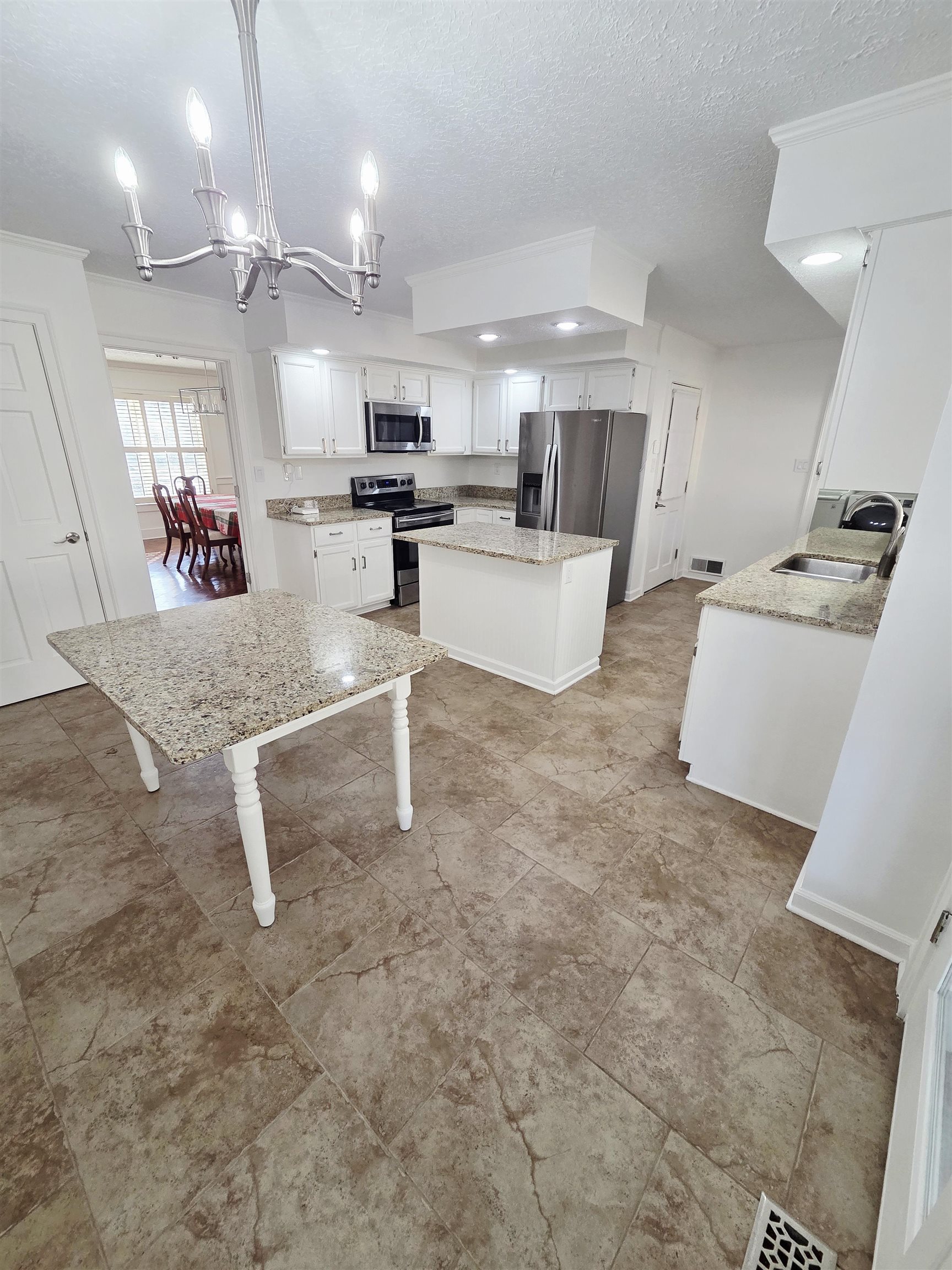 2095 Newfields Road Germantown, TN 38139 - Photo 10 of 34 Kitchen featuring stainless steel appliances, a center island, white cabinetry, light stone countertops, and suspended lighting