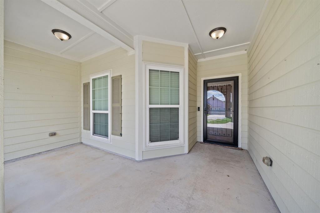 229 Firefly Drive Springtown, TX 76082 - Photo 23 of 33 Covered entry porch featuring light-colored siding, two windows with shutters, and a black security screen door