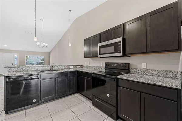 a kitchen with stainless steel appliances granite countertop wooden cabinets a stove a microwave and a sink