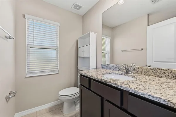 a bathroom with a granite countertop sink toilet and mirror