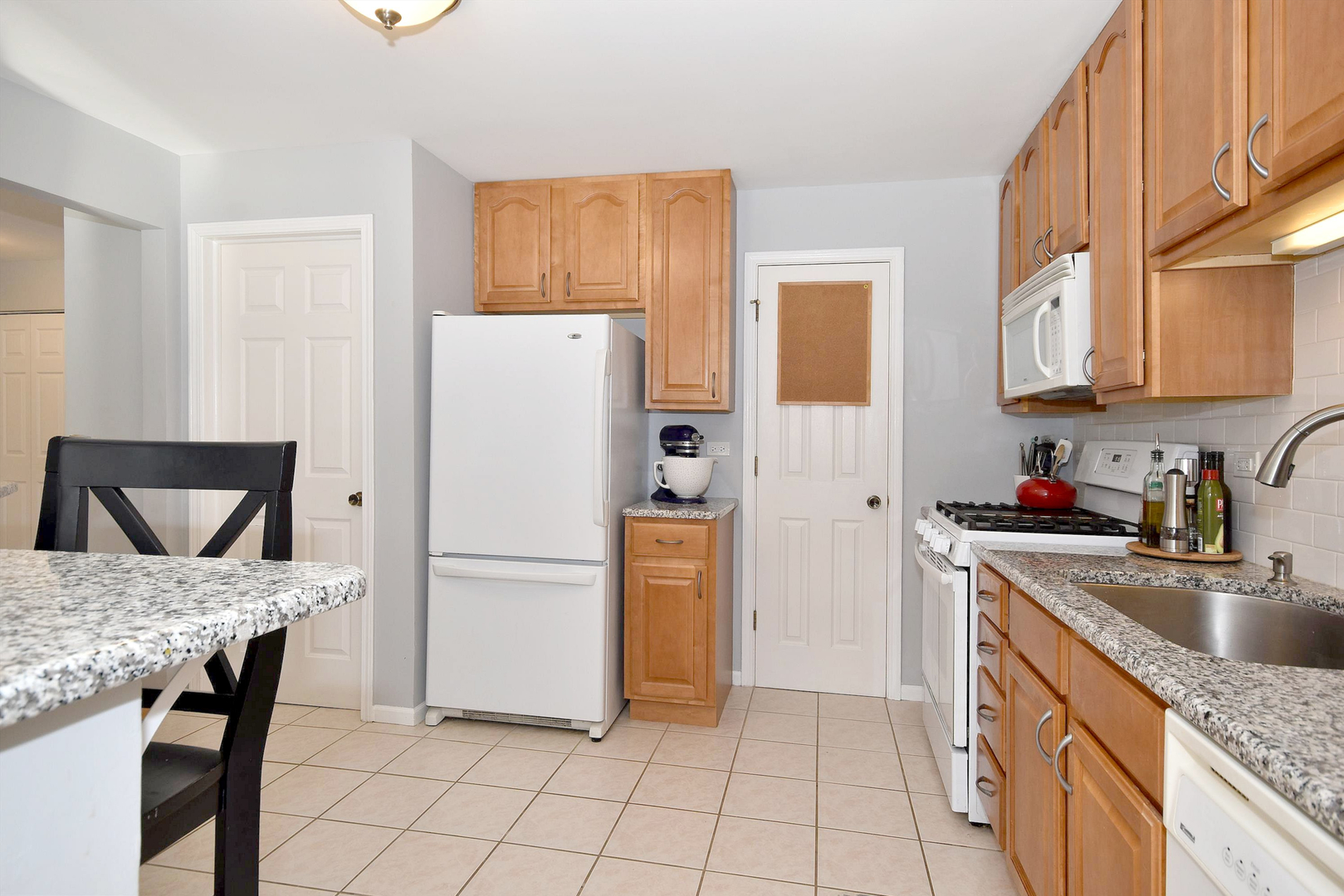 1622 Hadley Court, Unit C1 Wheeling, IL 60090 - Photo 6 of 32 a kitchen with a refrigerator a microwave and wooden cabinets