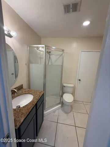 a bathroom with a granite countertop sink toilet a mirror and shower