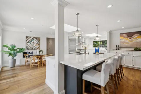 a kitchen with stainless steel appliances kitchen island granite countertop a table chairs sink and wooden floor