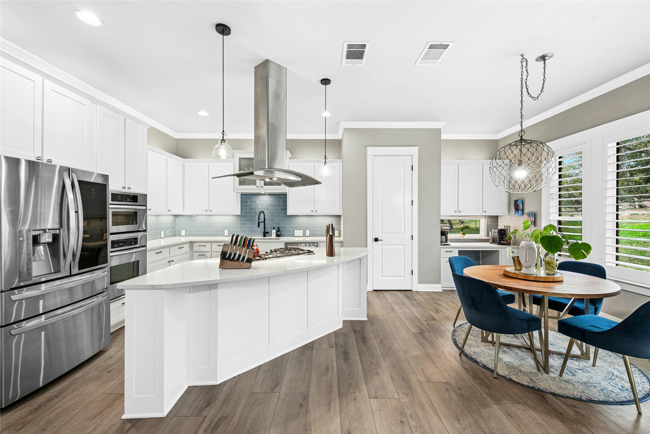 279 Rugged Earth Drive Austin, TX 78737 - Photo 16 of 40 Kitchen featuring stainless steel appliances, island exhaust hood, backsplash, white cabinets, and ornamental molding