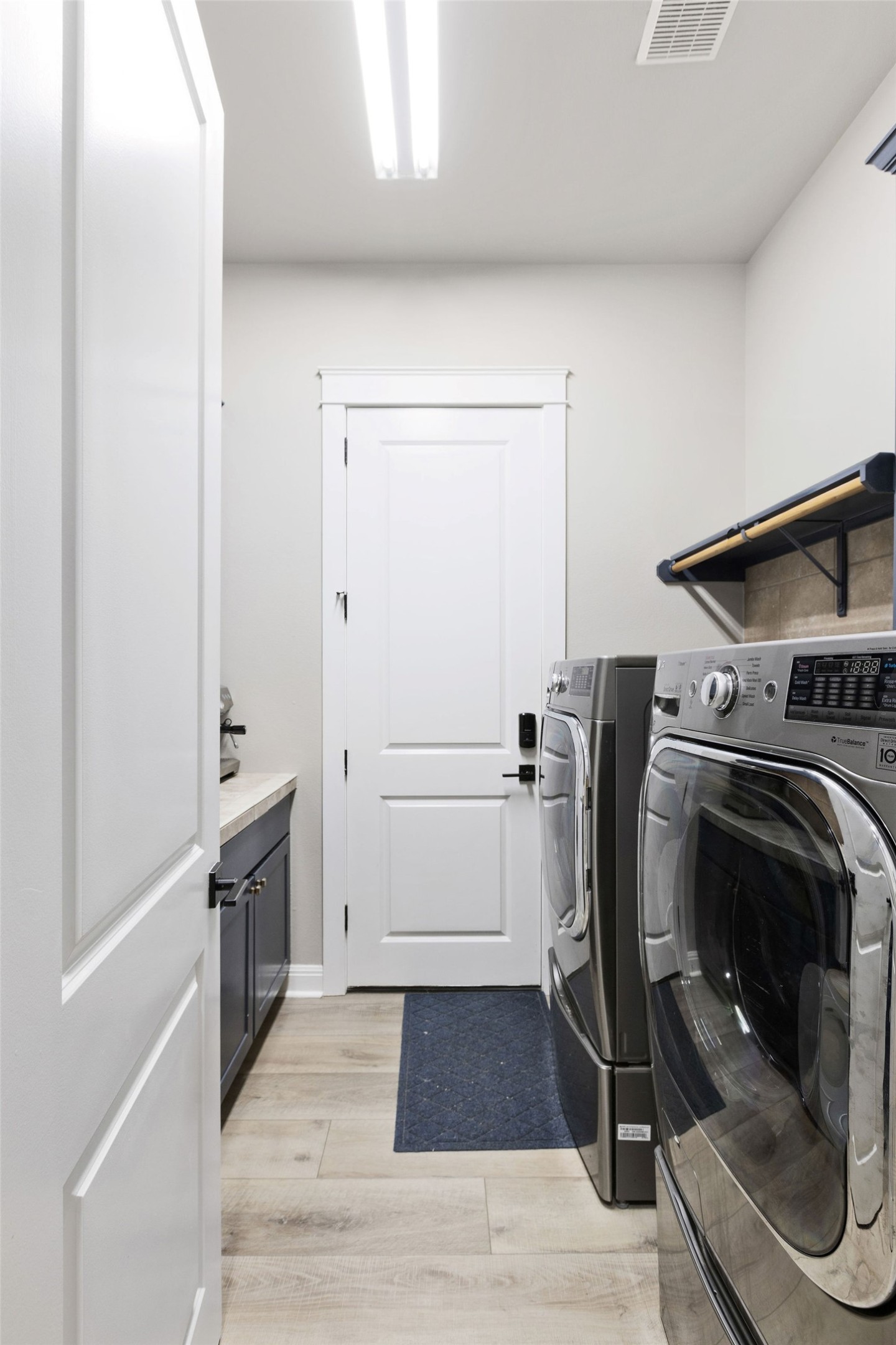 279 Rugged Earth Drive Austin, TX 78737 - Photo 30 of 40 Laundry room with washer and clothes dryer, light wood-style floors, and cabinet space