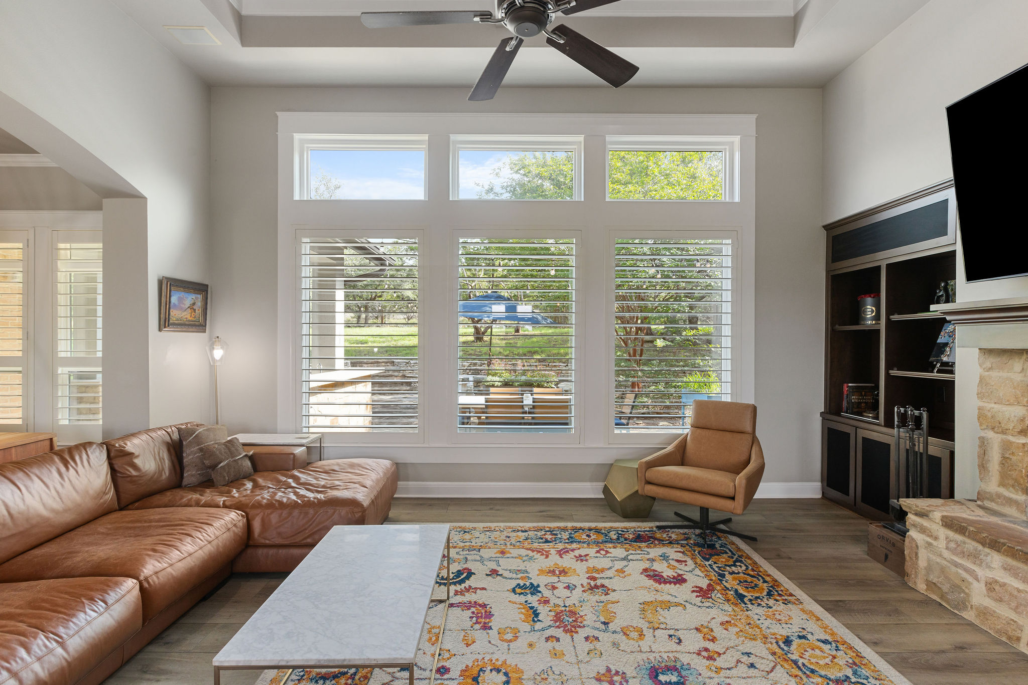 279 Rugged Earth Drive Austin, TX 78737 - Photo 6 of 40 Living room with a ceiling fan, wood finished floors, a fireplace, a towering ceiling, and arched walkways