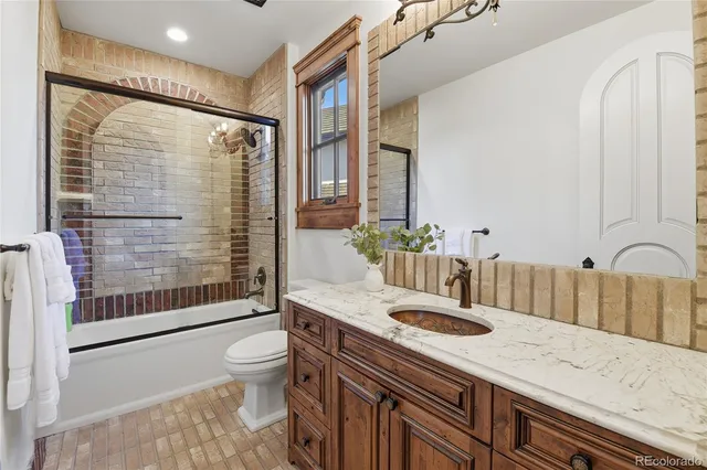 a bathroom with a granite countertop sink a toilet a mirror and shower