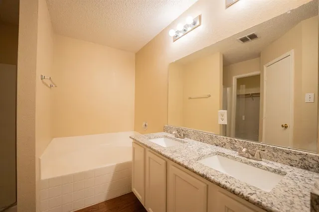 a bathroom with a granite countertop sink and a bathtub