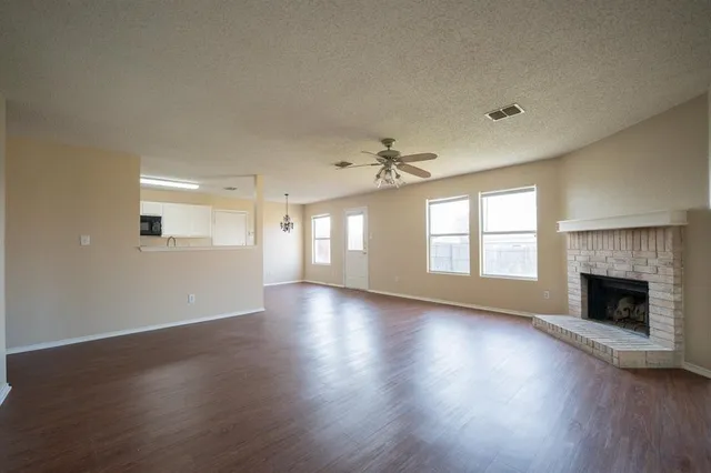 an empty room with wooden floor fireplace and windows