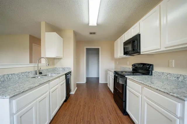 a kitchen with granite countertop kitchen island stainless steel appliances a sink dishwasher stove microwave and cabinets