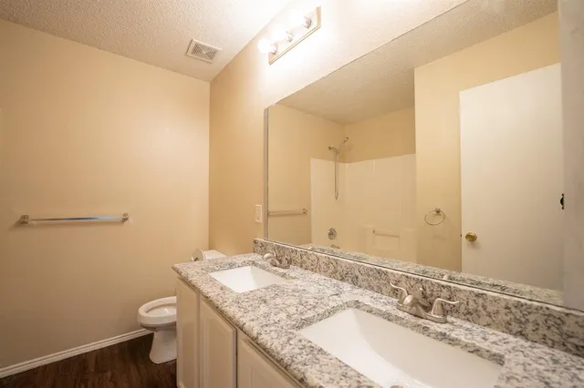 a bathroom with a granite countertop sink a toilet and a mirror