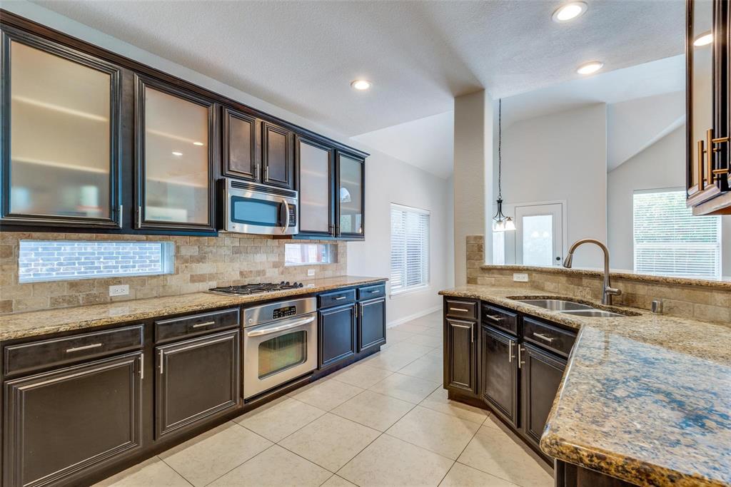 2344 Ranchview Drive Little Elm, TX 75068 - Photo 9 of 24 Kitchen featuring dark wood cabinetry, granite countertops, tile backsplash, and stainless steel appliances including a built-in oven and microwave