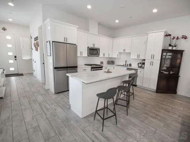 a kitchen with stainless steel appliances a refrigerator a stove a sink dishwasher and a refrigerator with wooden floor