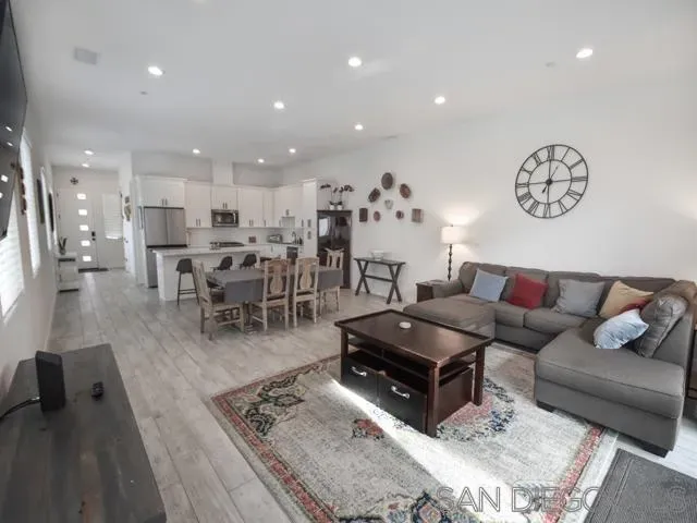 a living room with furniture and a dining table with wooden floor
