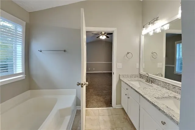 a bathroom with a granite countertop sink mirror and a bath tub