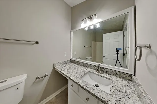 a bathroom with a granite countertop sink a toilet and a mirror