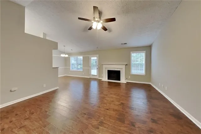 an empty room with wooden floor fireplace and windows