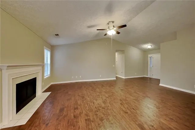 a view of an empty room with wooden floor and a fireplace