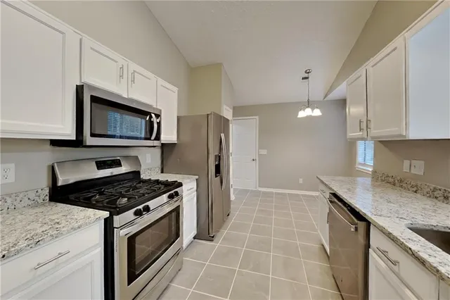 a kitchen with granite countertop a stove a sink and a microwave