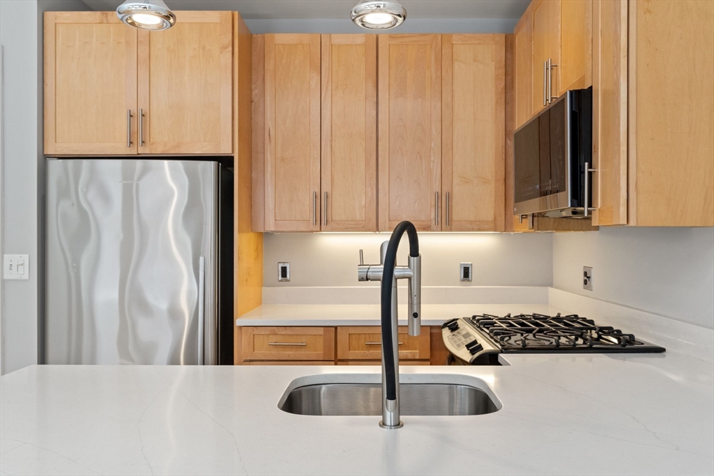 70 Lincoln Street, Unit L515 Boston, MA 02111 - Photo 7 of 16 a kitchen with a sink a stove and a refrigerator with wooden floor