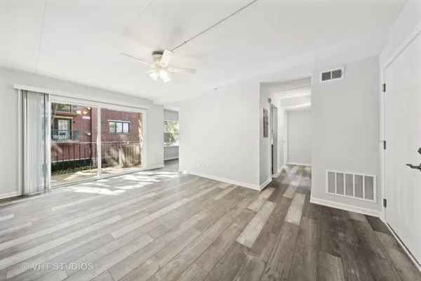 a view of empty room with wooden floor and fan