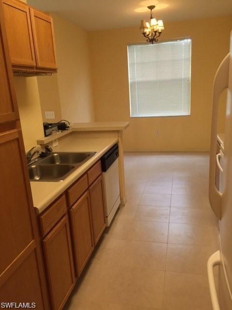 Kitchen with light countertops, dishwasher, wood finish cabinetry, fridge, and suspended lighting