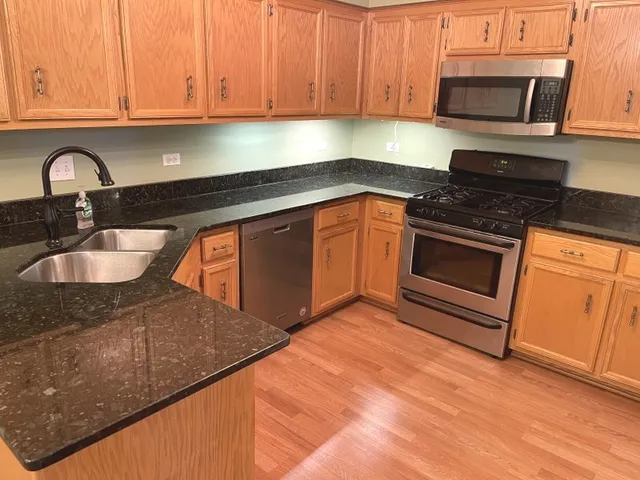 a kitchen with granite countertop a sink stainless steel appliances and cabinets