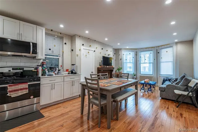 a kitchen with stainless steel appliances granite countertop a stove top oven a sink dishwasher a dining table and chairs with wooden floor