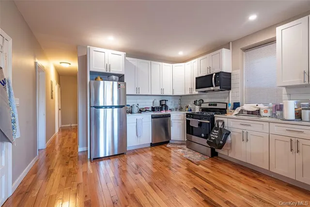 a kitchen with a refrigerator a stove top oven a sink and dishwasher with wooden floor