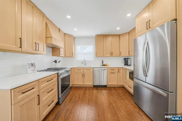 a kitchen with white cabinets stainless steel appliances and wooden floor