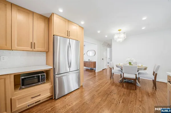 a kitchen with stainless steel appliances granite countertop a stove a refrigerator a microwave a dining table and chairs with wooden floor