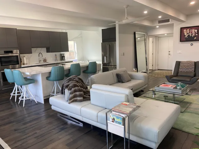 a living room with stainless steel appliances kitchen island granite countertop a table chairs sink and window