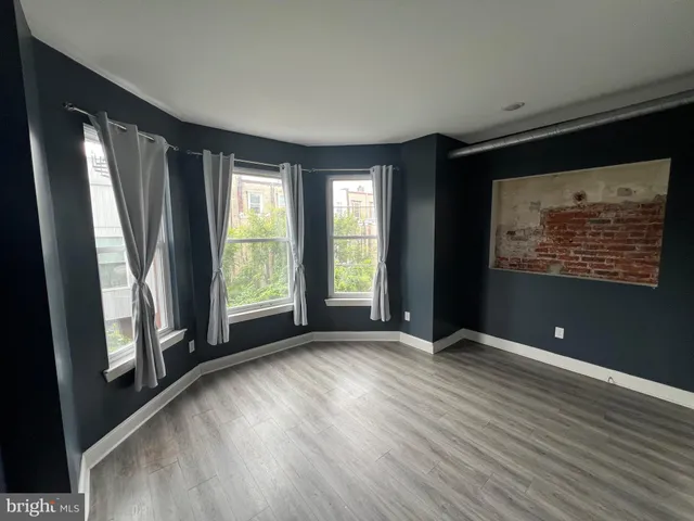 a view of an empty room with glass door and wooden floor