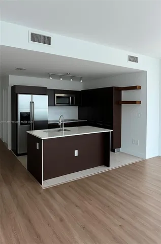 a kitchen with stainless steel appliances kitchen island a sink dishwasher and a refrigerator