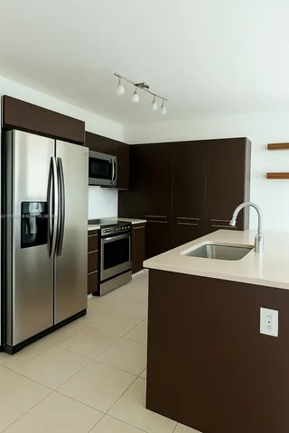 a kitchen with stainless steel appliances a refrigerator a sink a stove and microwave