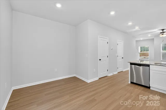 a view of an empty room with window and wooden floor