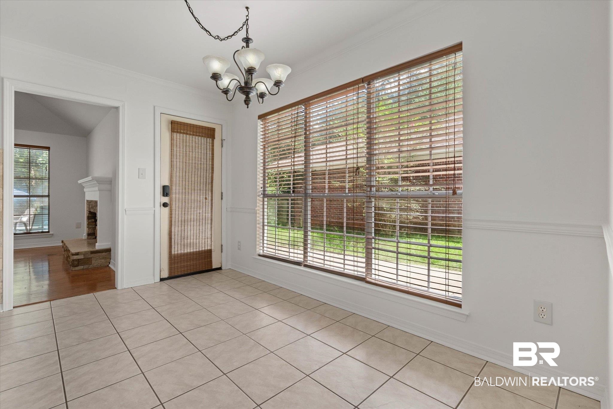 3032 Autumn Ridge Drive West Mobile, AL 36695 - Photo 4 of 20 Unfurnished dining area featuring a chandelier, crown molding, light tile patterned flooring, and a fireplace