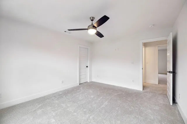 an empty room with a ceiling fan and carpet
