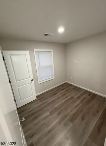 an empty room with wooden floor and white walls