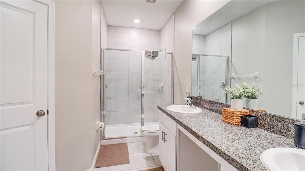 31632 Blue Passing Loop Wesley Chapel, FL 33545 - Photo 30 of 48 a bathroom with a granite countertop sink a toilet a mirror and shower