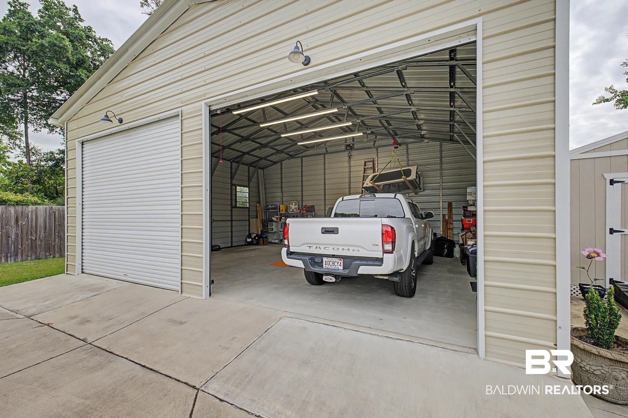 2808 Pine Ridge Drive Lillian, AL 36549 - Photo 27 of 47 Large detached garage featuring corrugated metal siding, two roll-up doors, concrete flooring, and interior fluorescent lighting