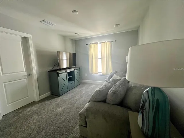 a living room with a bed and a refrigerator