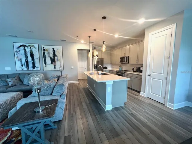 a large kitchen with cabinets wooden floor and stainless steel appliances