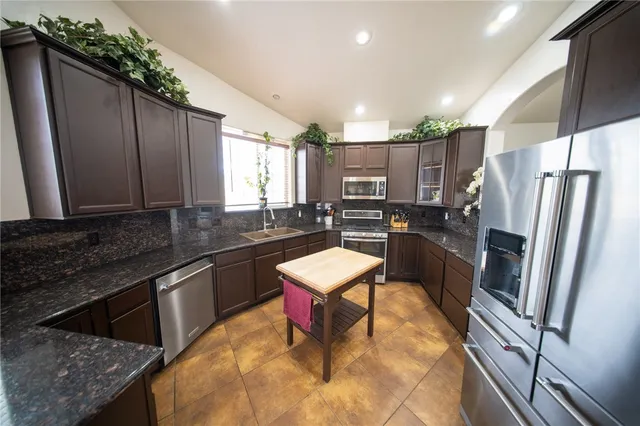 a kitchen with stainless steel appliances granite countertop a refrigerator sink and stove