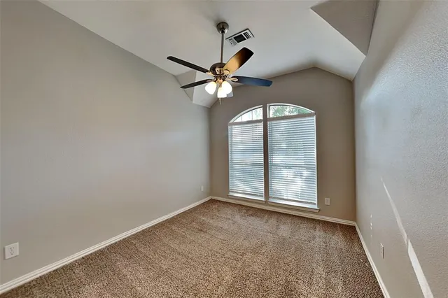 an empty room with a chandelier fan and windows