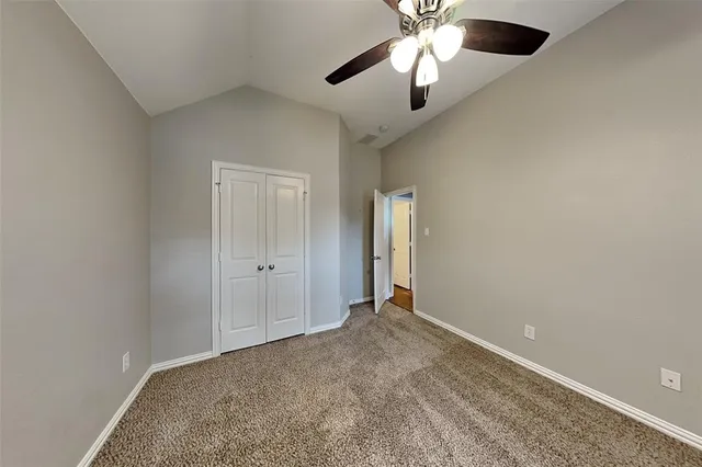 an empty room with closet and a chandelier fan