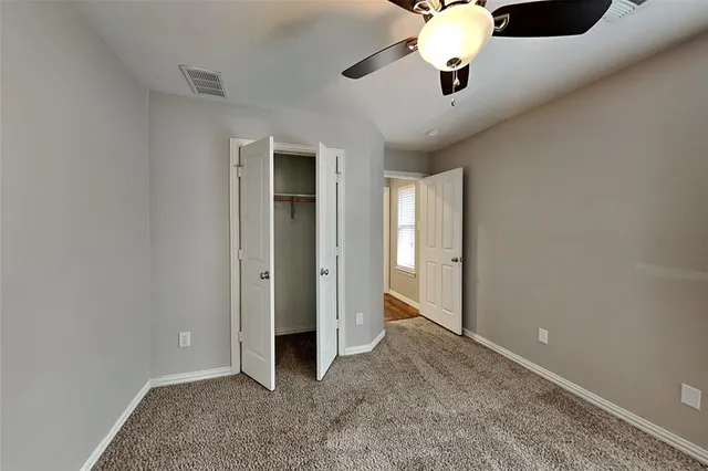 an empty room with closet and a chandelier fan